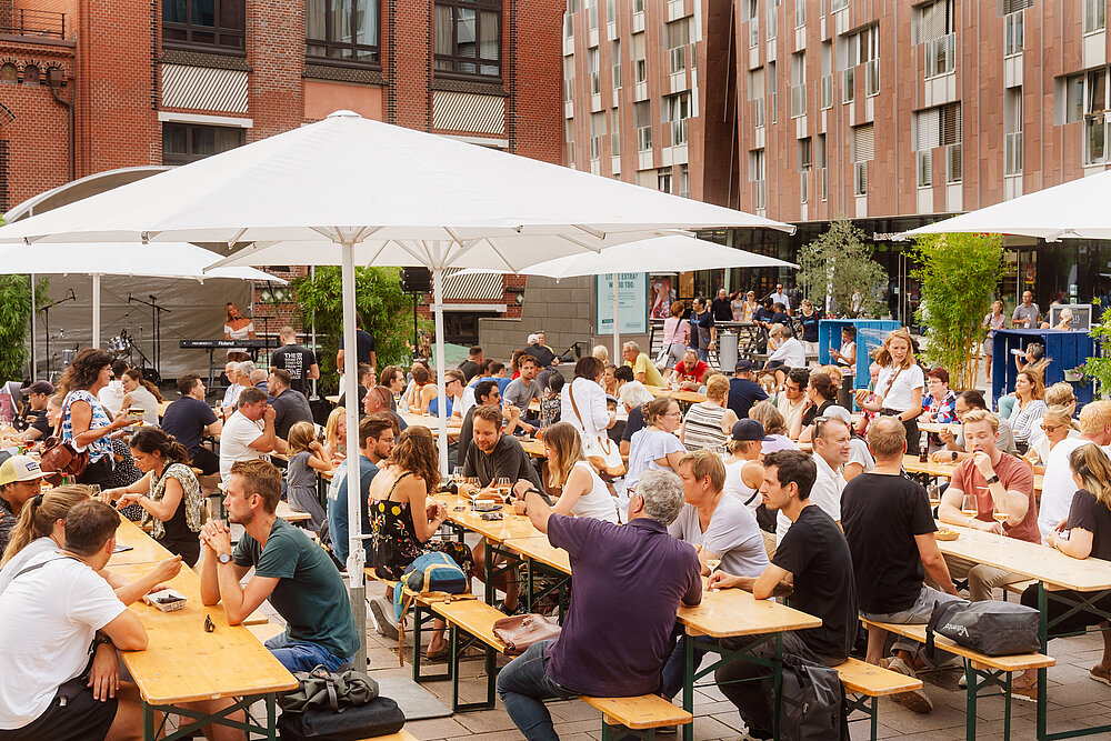 Das Bild zeigt Menschen beim Weinfest auf dem Marktplatz des Überseeboulevards.